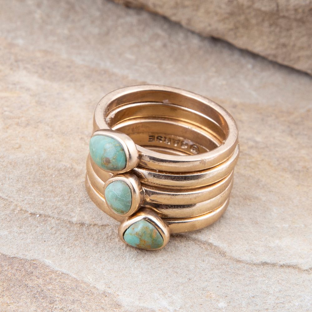 Set of stacking rings featuring blue turquoise and gold accents from Barse Jewelry, arranged in a layered display.