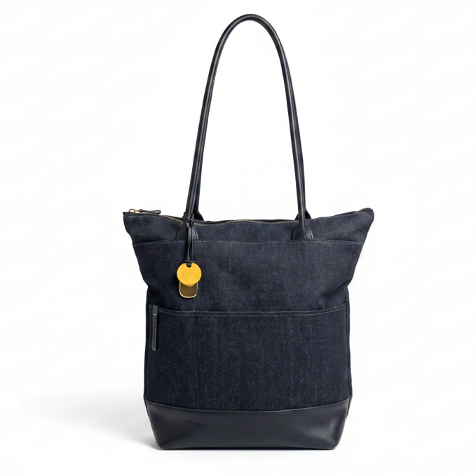Large denim and black leather tote handbag by R. Riveter, featuring sturdy handles and spacious interior for everyday use.